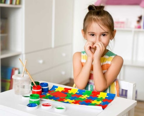 A young girl paints a colorful puzzle picture.