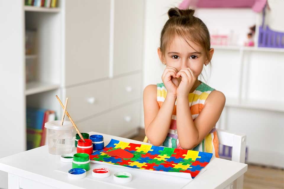 A young girl paints a colorful puzzle picture.