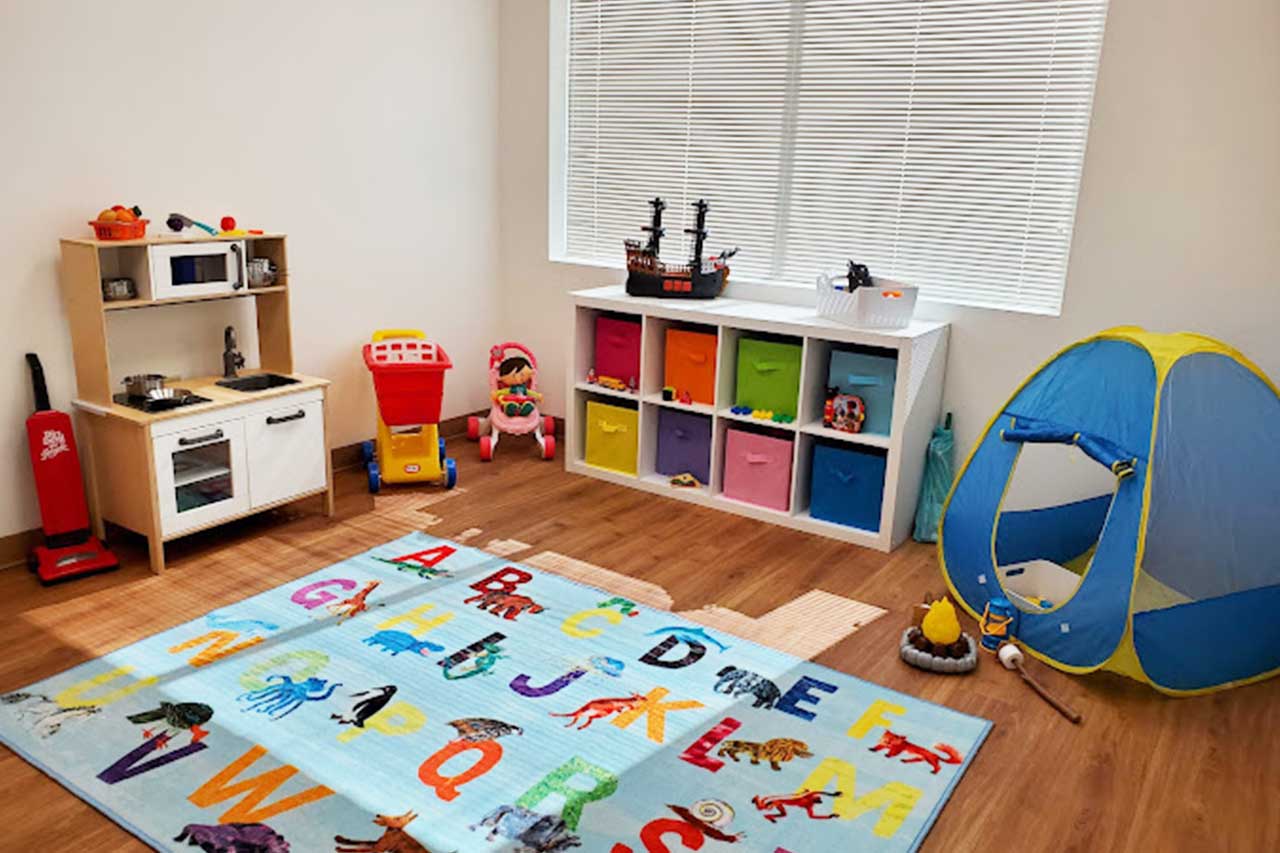 Colorful room with bins, an alphabet rug, small kitchen, and blue and yellow tent.