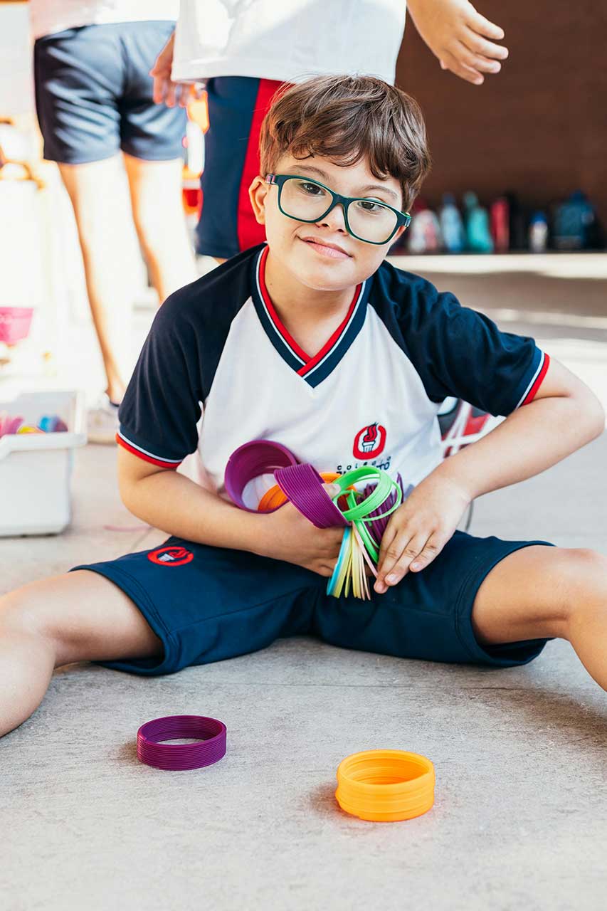 a young boy with glasses holding slinkies