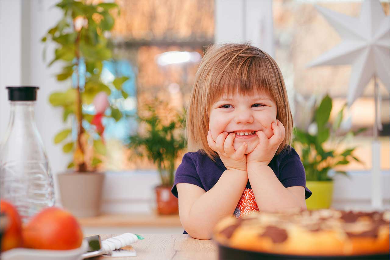 little child smiling with their hands on their face